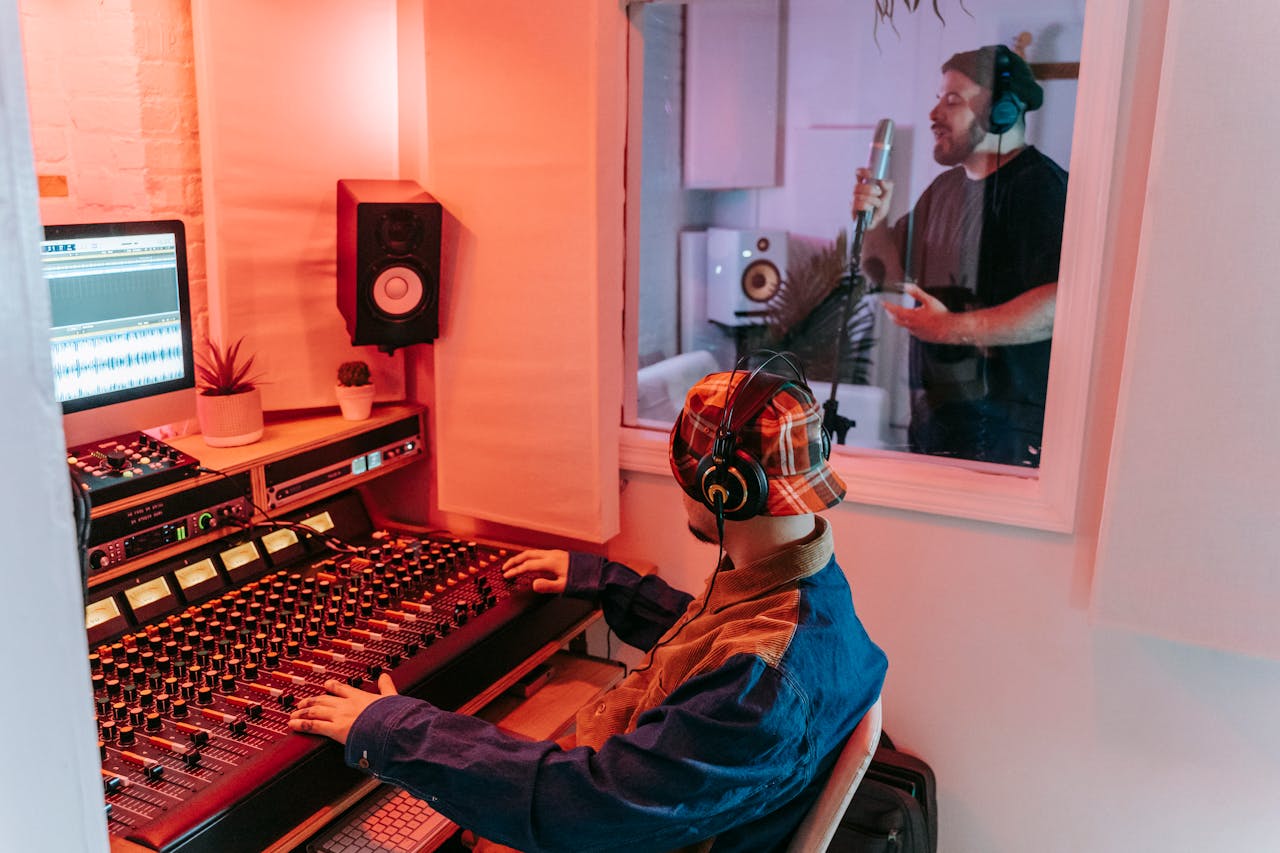 Two men engaged in a vocal recording session in a modern music studio, highlighting sound equipment.